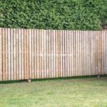 Wooden palisade fencing. Timber hit and miss fence.